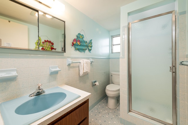 bathroom with a shower with door, vanity, tile patterned flooring, and toilet