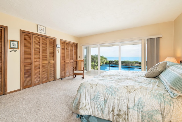 bedroom with multiple closets, a water view, carpet flooring, and access to outside