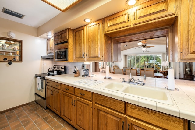 kitchen featuring sink, ceiling fan, appliances with stainless steel finishes, tasteful backsplash, and tile counters