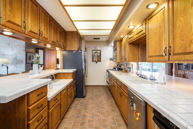 kitchen featuring appliances with stainless steel finishes, tile counters, sink, and decorative backsplash