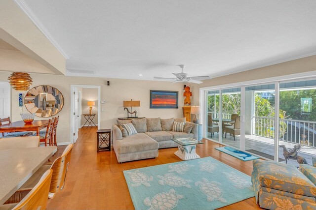 living room with crown molding, ceiling fan, and light wood-type flooring