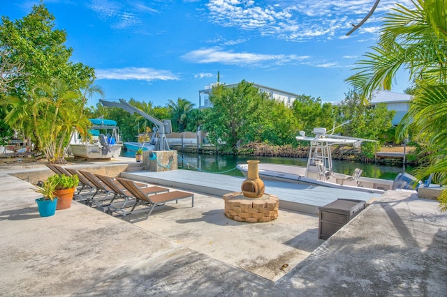 view of patio / terrace featuring a fire pit, a dock, and a water view