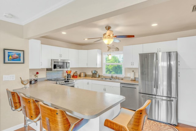 kitchen featuring sink, a breakfast bar area, appliances with stainless steel finishes, kitchen peninsula, and white cabinets