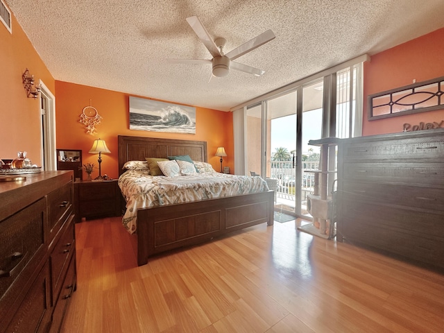 bedroom with a wall of windows, light wood finished floors, ceiling fan, a textured ceiling, and access to outside