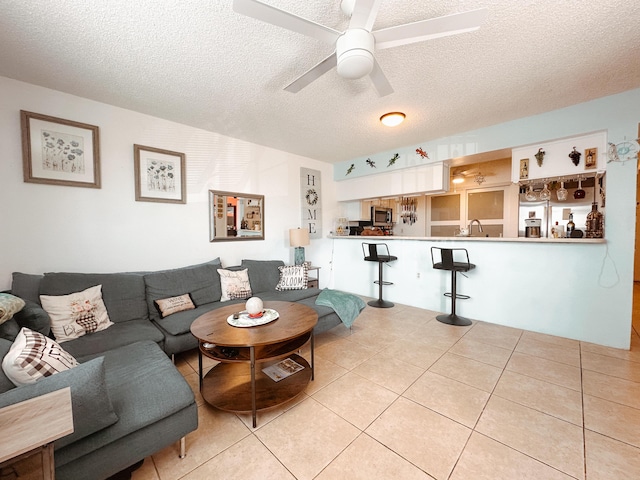 living area featuring a textured ceiling, light tile patterned flooring, and a ceiling fan