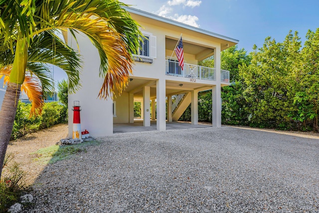872 La Paloma Rd, Key Largo, FL 33037 - view of front of property featuring a carport, stairway, gravel driveway, and stucco siding