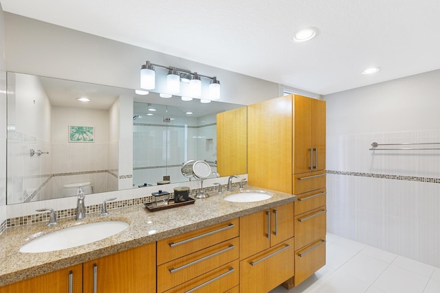 bathroom featuring a shower with door, tile walls, vanity, tile patterned floors, and toilet