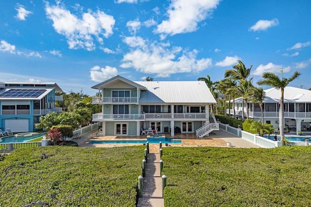 back of property featuring a pool with hot tub, a yard, a patio, and a balcony