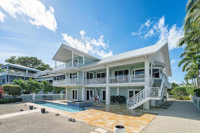 rear view of house with a patio, a balcony, and a pool with hot tub