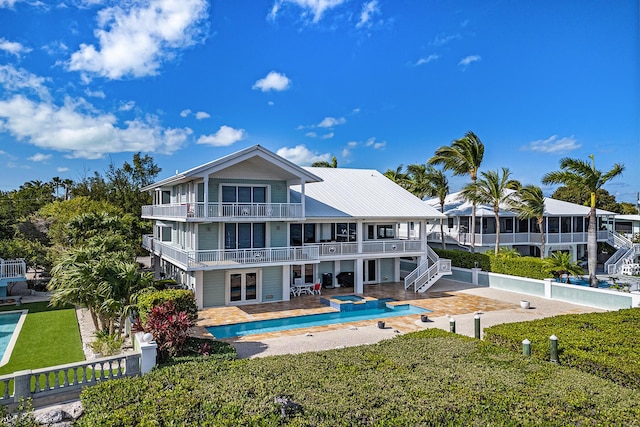 back of property with french doors, a patio, a balcony, and a pool with hot tub