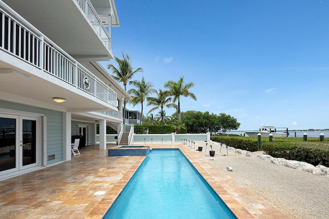 view of swimming pool featuring a patio, a water view, and an in ground hot tub