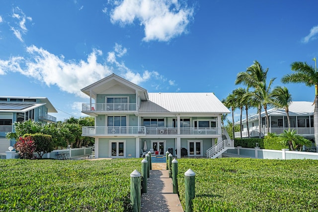 view of front of home featuring french doors, a balcony, and a front yard