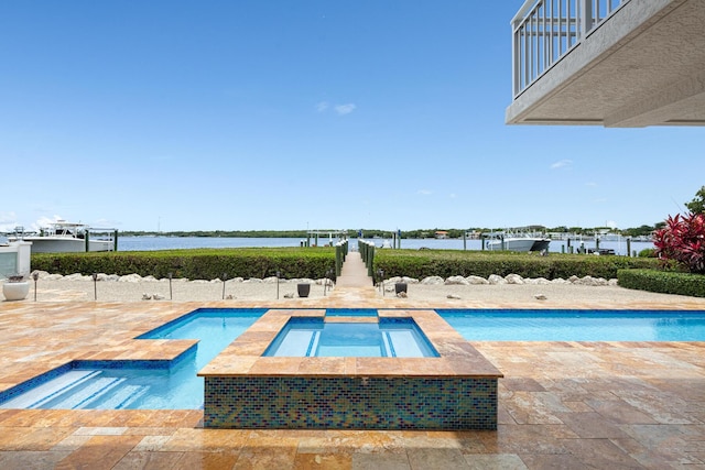 view of swimming pool featuring an in ground hot tub, a water view, and a patio