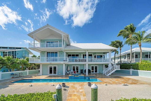 rear view of property with a swimming pool with hot tub, a patio, a balcony, and french doors