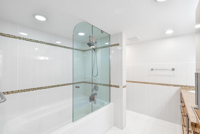 bathroom with combined bath / shower with glass door, tile walls, tile patterned flooring, vanity, and a textured ceiling