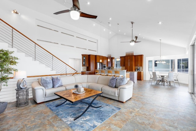 living room with ceiling fan with notable chandelier and high vaulted ceiling