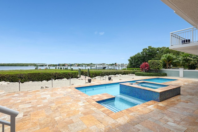 view of pool featuring a patio area, an in ground hot tub, and a water view