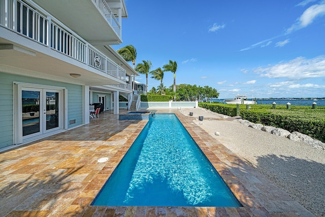 view of swimming pool featuring an in ground hot tub, a water view, and a patio area