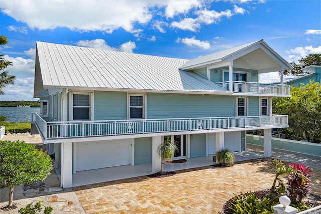 beach home with a garage, a balcony, and a water view