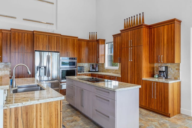 kitchen with stainless steel appliances, a center island, sink, and light stone countertops