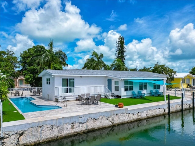 back of house featuring a water view, a fenced in pool, a patio, and a lawn