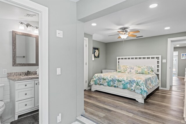 bedroom featuring ceiling fan, ensuite bathroom, sink, and hardwood / wood-style floors