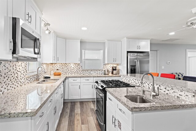 kitchen featuring stainless steel appliances, sink, decorative backsplash, and white cabinets