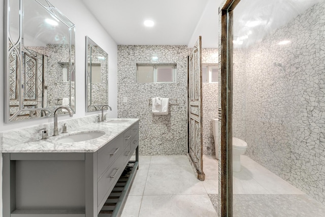 bathroom with vanity, toilet, tile patterned flooring, and tile walls