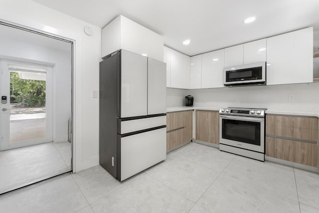 kitchen with white appliances, white cabinets, and light tile patterned flooring