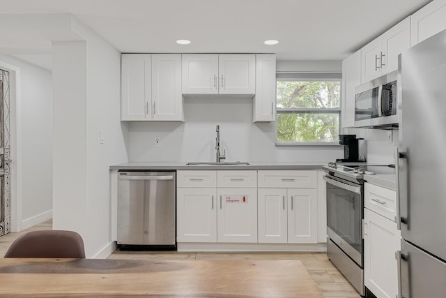 kitchen featuring white cabinetry, appliances with stainless steel finishes, sink, and light wood-type flooring