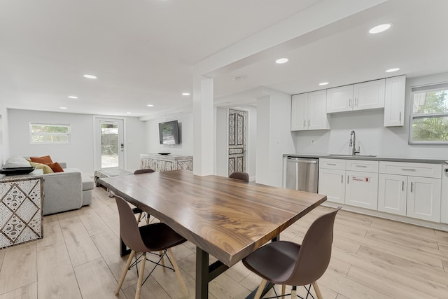 dining room with sink, a healthy amount of sunlight, and light wood-type flooring