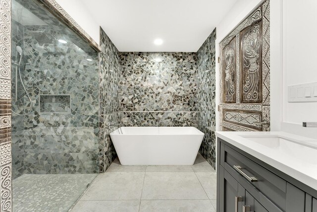 bathroom with a tub to relax in, tile patterned flooring, tile walls, and vanity