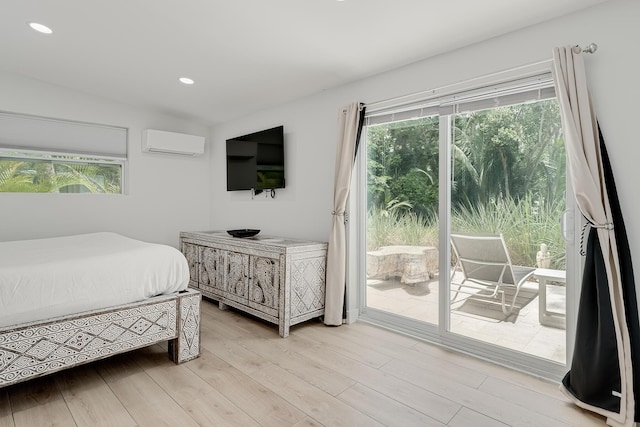 bedroom featuring multiple windows, a wall mounted AC, access to exterior, and light hardwood / wood-style flooring