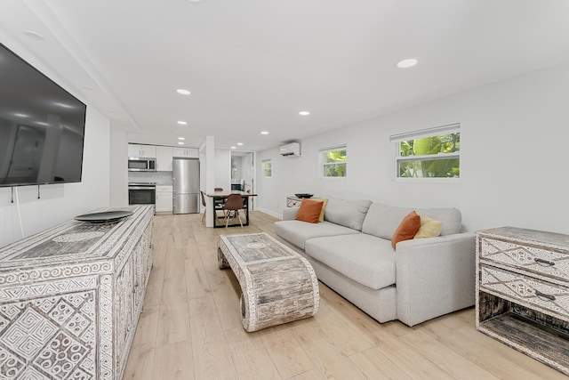 living room with a wall mounted AC and light hardwood / wood-style floors