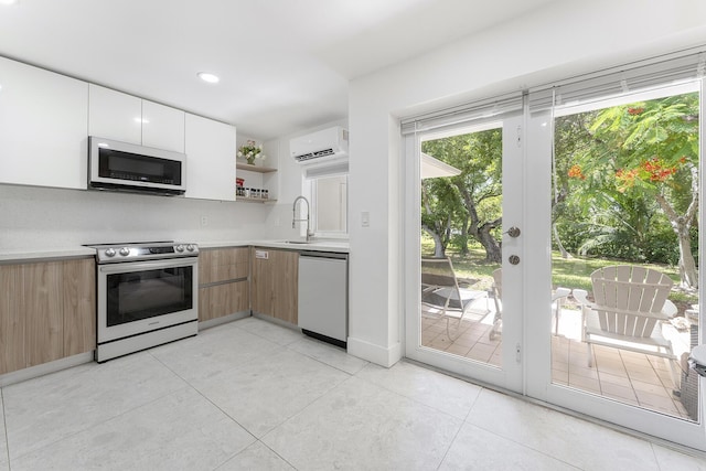 kitchen featuring sink, a wall mounted air conditioner, white cabinets, stainless steel appliances, and backsplash