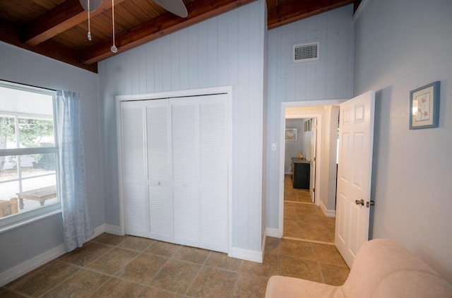 unfurnished bedroom with wood ceiling, wooden walls, beam ceiling, and a closet