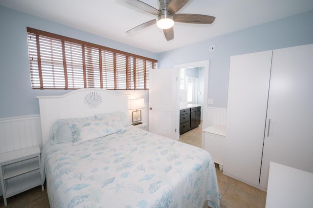 tiled bedroom featuring multiple windows, ceiling fan, and ensuite bathroom