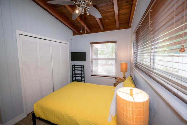 bedroom featuring beamed ceiling, wooden ceiling, and a closet