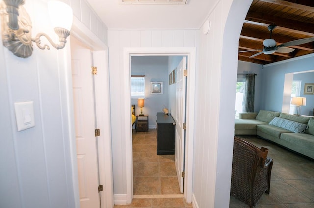 corridor featuring wood ceiling, beam ceiling, and light tile patterned floors