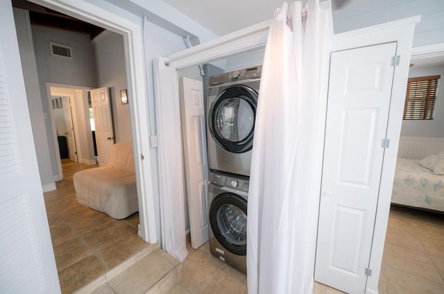 clothes washing area with stacked washing maching and dryer