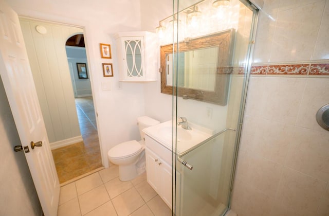 bathroom with vanity, toilet, a shower with shower door, and tile patterned flooring