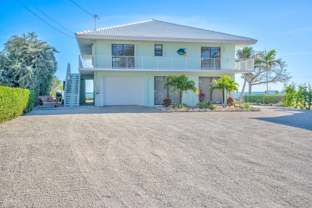 33 Kyle Way, Marathon, FL 33050 - coastal inspired home featuring dirt driveway, a tiled roof, stucco siding, stairs, and a balcony