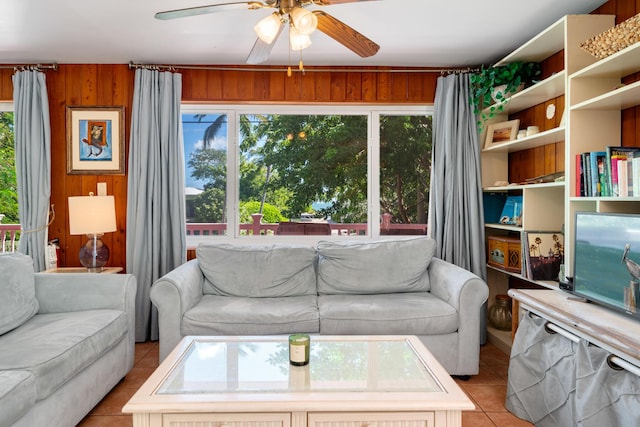 living room with ceiling fan, wooden walls, light tile patterned floors, and a wealth of natural light