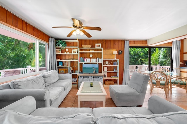 living room featuring ceiling fan, light tile patterned floors, and wooden walls