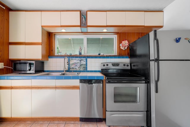 kitchen featuring backsplash, light tile patterned floors, stainless steel appliances, and sink