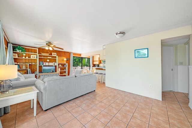 tiled living room featuring ceiling fan, built in features, and wood walls