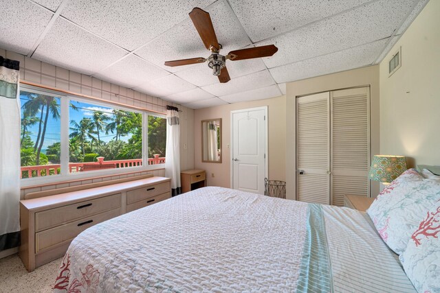 bedroom with a paneled ceiling, ceiling fan, and a closet