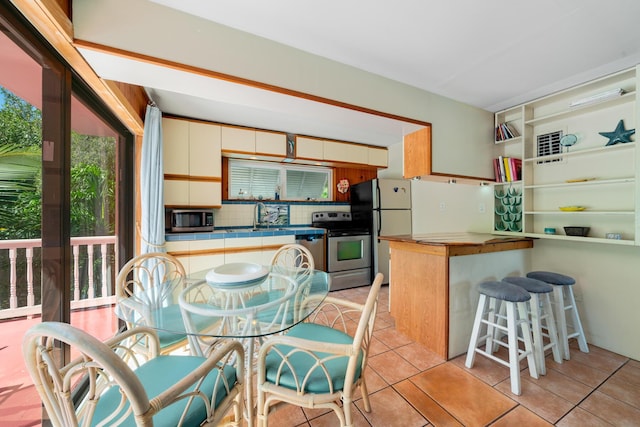 kitchen featuring light tile patterned flooring, appliances with stainless steel finishes, sink, decorative backsplash, and kitchen peninsula