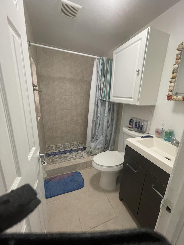 bathroom with walk in shower, vanity, toilet, and tile patterned flooring