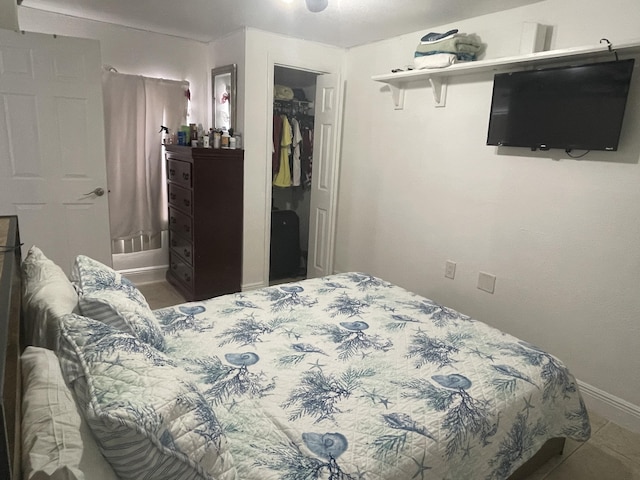 bedroom with a spacious closet, baseboards, and a closet